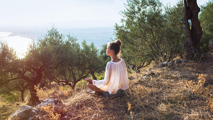 Woman meditating in an olive grove
